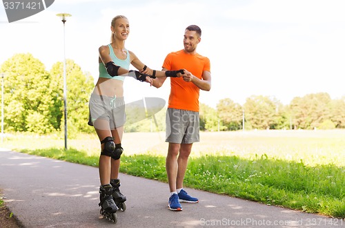 Image of happy couple with roller skates riding outdoors