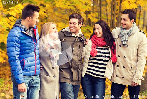 Image of group of smiling men and women in autumn park