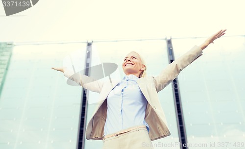 Image of young smiling businesswoman over office building