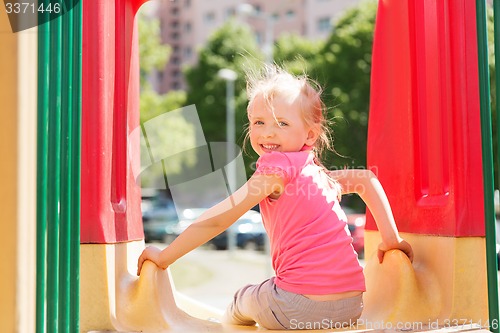 Image of happy little girl on slide at children playground