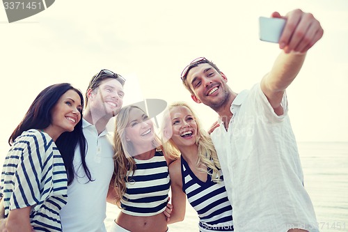 Image of happy friends on beach and taking selfie