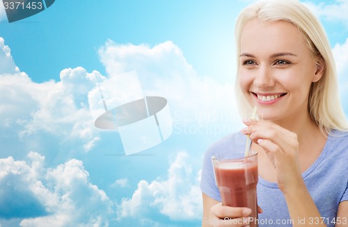 Image of smiling woman drinking juice or shake over sky