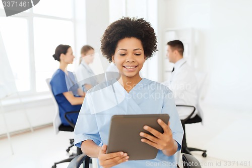 Image of happy nurse with tablet pc over team at hospital