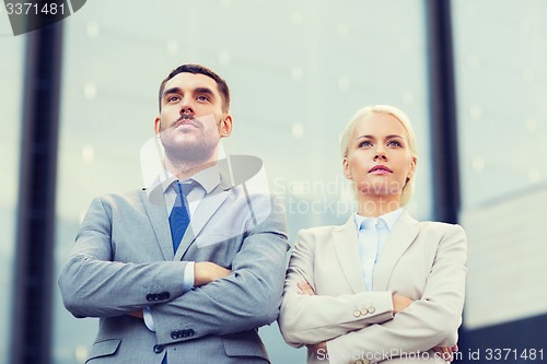 Image of serious businessmen standing over office building