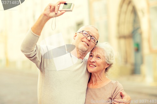 Image of senior couple photographing on city street