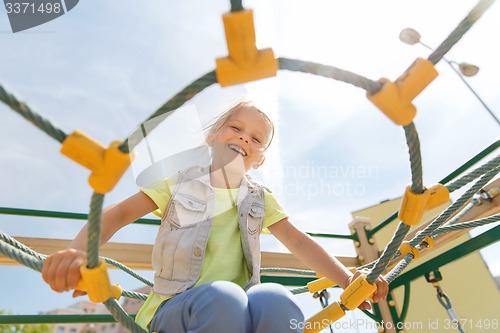 Image of happy little girl climbing on children playground