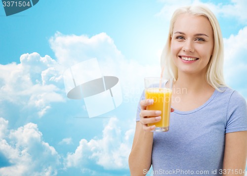 Image of smiling woman drinking orange juice over sky