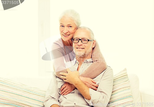 Image of happy senior couple hugging on sofa at home