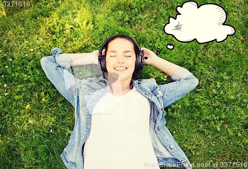 Image of smiling young girl in headphones lying on grass