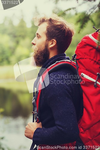 Image of smiling man with beard and backpack hiking