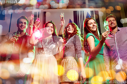 Image of smiling friends with glasses of champagne in club