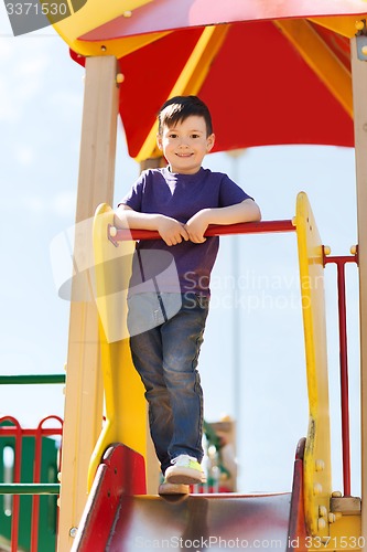 Image of happy little boy climbing on children playground