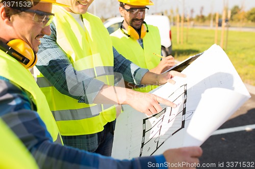 Image of close up of builders with blueprint at building