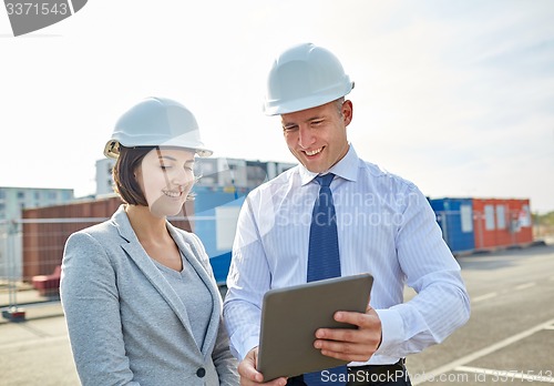 Image of happy builders in hardhats with tablet pc outdoors