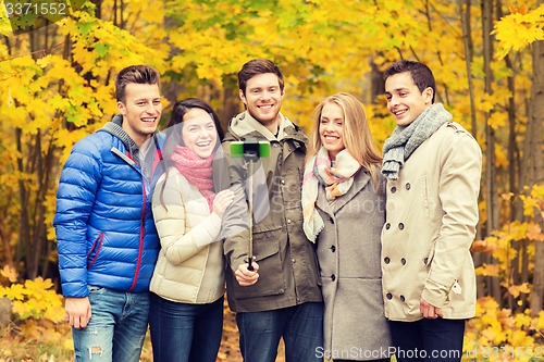 Image of smiling friends with smartphone in city park