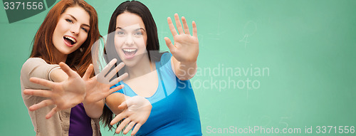 Image of happy student girls showing their palms over green