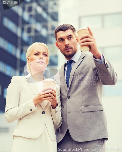 Image of serious businessmen with paper cups outdoors