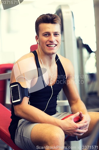 Image of smiling sportsman with smartphone and earphones