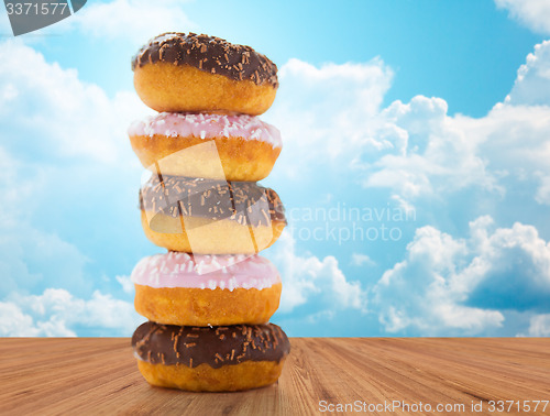 Image of close up of glazed donuts pile over blue sky
