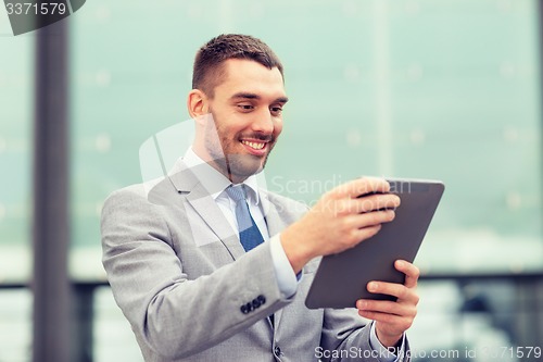 Image of smiling businessman with tablet pc outdoors