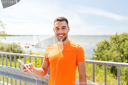 Image of smiling young man with smartphone and earphones