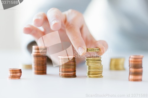 Image of close up of female hand putting coins into columns