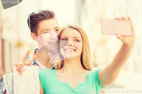 Image of smiling couple with smartphone in city