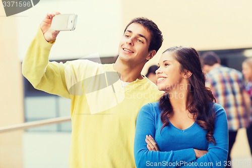 Image of group of smiling students with smartphone outdoors