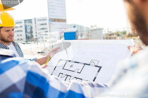 Image of close up of builders with blueprint at building