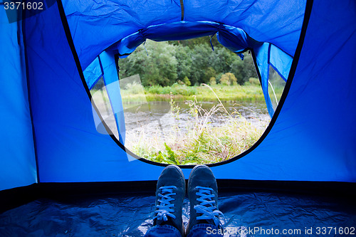 Image of close up of camper legs lying near tent entrance