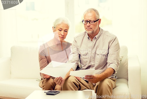 Image of senior couple with papers and calculator at home