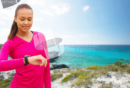 Image of smiling woman with heart rate watch on beach