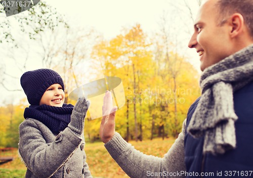 Image of happy father and son making high five in park