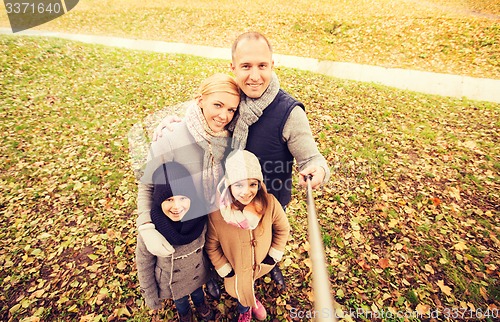 Image of happy family with selfie stick in autumn park