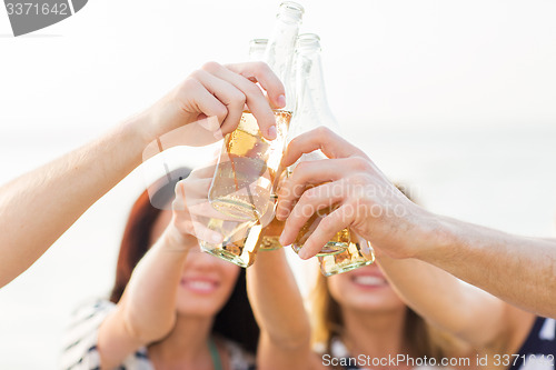 Image of close up of friends clinking bottles with drinks