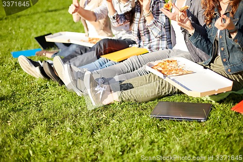 Image of close up of teenage students eating pizza on grass