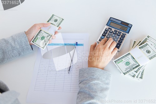 Image of close up of hands counting money with calculator