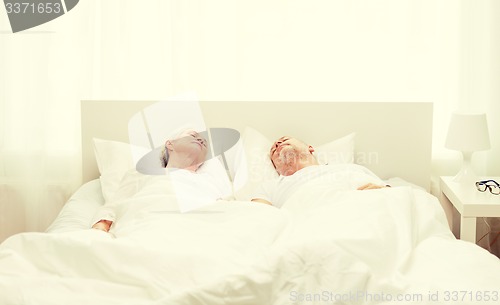 Image of happy senior coupler lying in bad at home