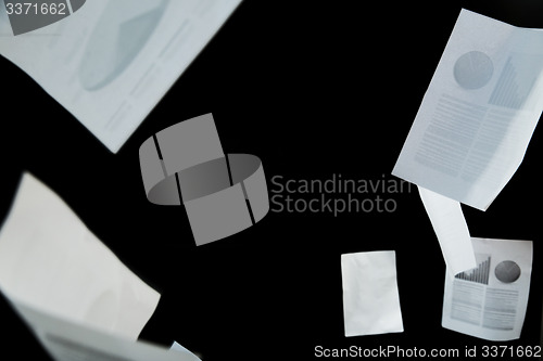 Image of business papers falling down over black background