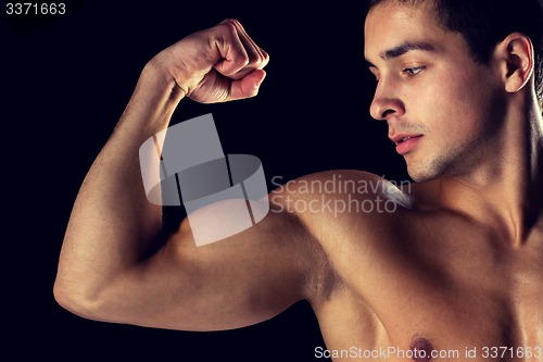 Image of close up of young man showing biceps