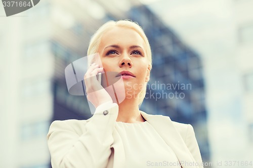 Image of serious businesswoman with smartphone outdoors