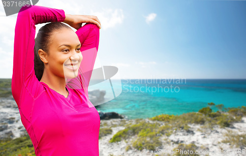 Image of smiling african woman stretching hand on beach