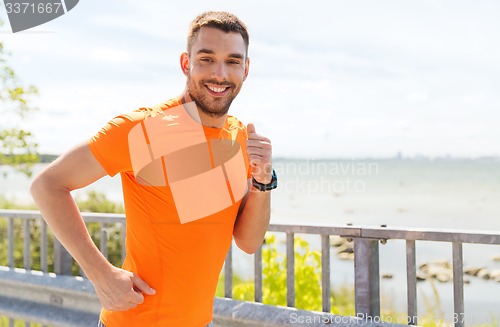 Image of smiling young man running at summer seaside