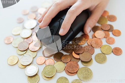 Image of close up of hand with computer mouse on money