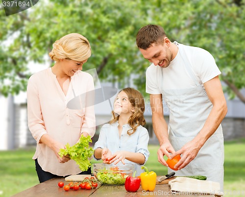 Image of happy family cooking vegetable salad for dinner