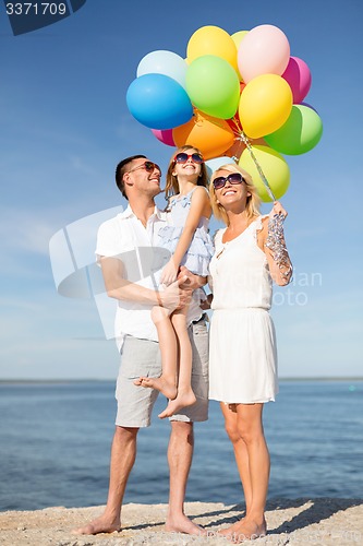 Image of happy family with colorful balloons at seaside