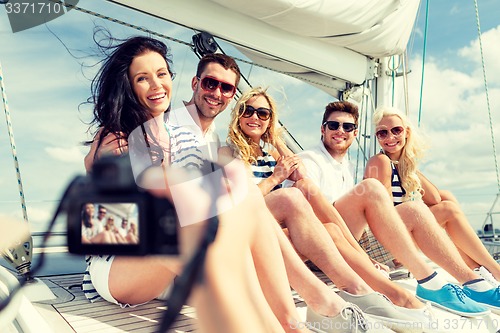 Image of smiling friends photographing on yacht