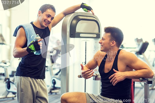 Image of smiling men exercising on gym machine