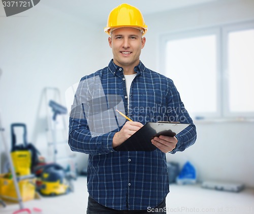 Image of smiling male builder in helmet with clipboard