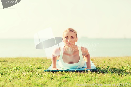 Image of young woman making yoga exercises outdoors